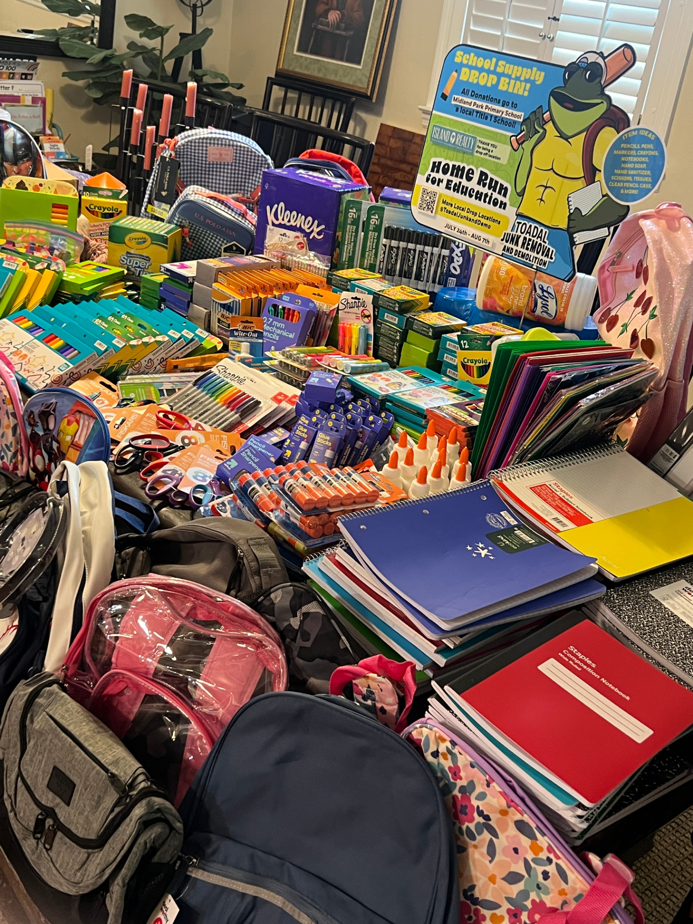 Table piled with donated school supplies and backpacks